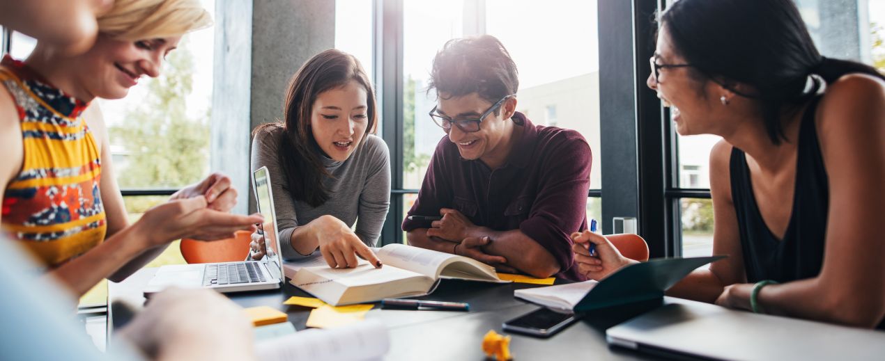 Gruppe von Studierenden arbeitet motiviert an einem Projekt und bespricht Tipps, wie man Bachelorarbeiten schreiben lassen sinnvoll nutzt